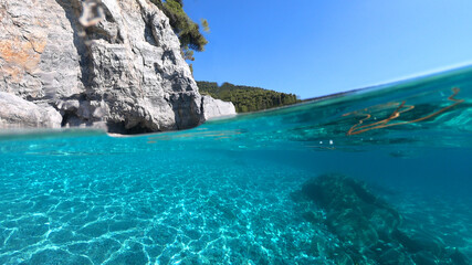 Sea level and underwater photo of caves and rocky nature in famous turquoise pebble beach of Kastani where famous Mamma Mia movie was filmed, Skopelos island, Sporades, Greece