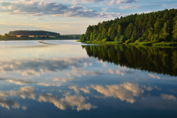 Fototapeta na wymiar Beautiful tranquil lake with cloud reflection. Reservoir Petrovichi on the Volma river, Minsk region, Belarus.