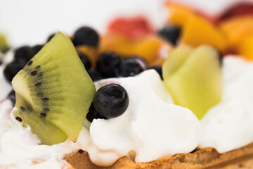 A close-up of fruit and whipped cream on a waffle.