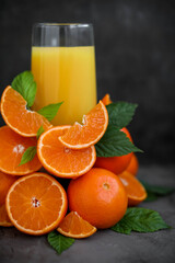 Fresh orange juice.  A glass of orange juice. Lots of orange slices. Minimalism. Dark gray background. 