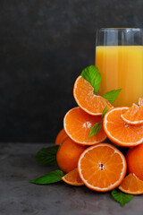 A glass of orange juice. Lots of orange slices. Minimalism. Dark gray background.