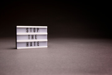 Sign that says Stop The Hate, with copy space to the right and shot in studio with dramatic lighting.