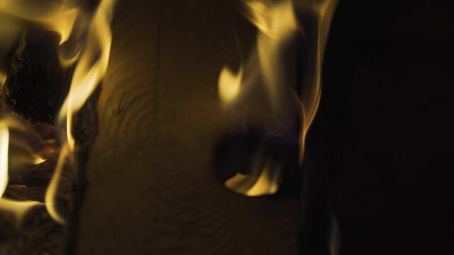 Fire eating through knothole of firewood, 4k