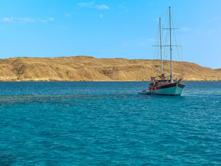 Obraz premium A sailing ship basks in the crystal clear waters around Tiran island in the Red Sea near Sharm El Sheik, Egypt in summer