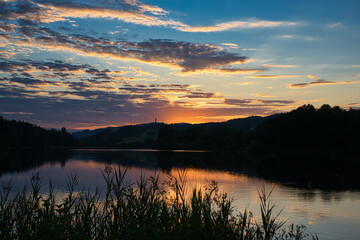 sonnenuntergang mit dramatischem wolkenhimmel spiegelnd im wasser an einem abendlichen see