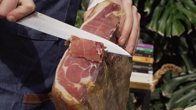 Hombre cortando jamon en una cocina al aire libre