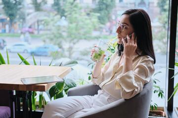 smiling businesswoman talking cellphone in city cafe - 367621911