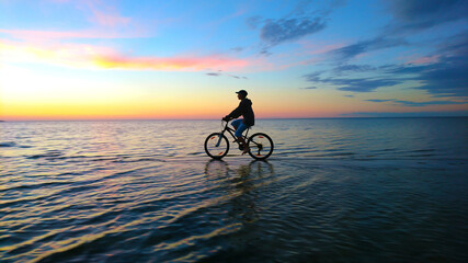 Fototapeta premium silhouette of a cyclist on the sea during sunset