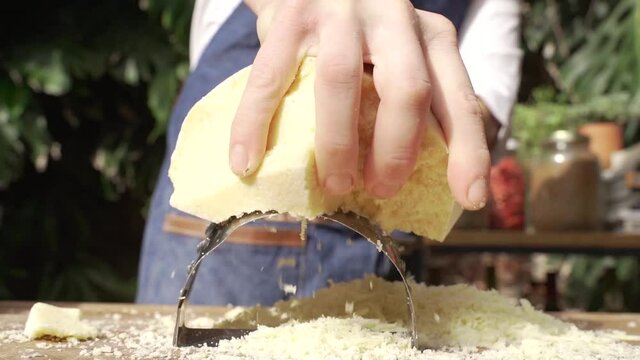 Hombre rayando queso duro en una tabla de madera 