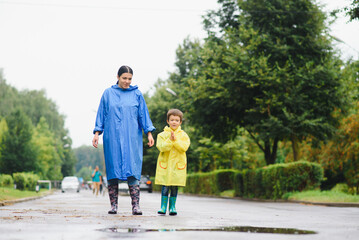 Obraz premium Mom and son in raincoats have fun together in the rain. concept of family vacation and happy childhood.