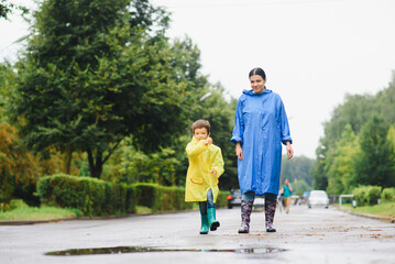 Mother and child, boy, playing in the rain, wearing boots and raincoats