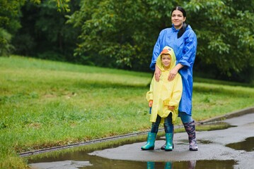 Mother and child, boy, playing in the rain, wearing boots and raincoats