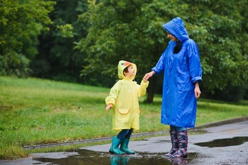 Fototapeta premium Mom and son in raincoats have fun together in the rain. concept of family vacation and happy childhood.