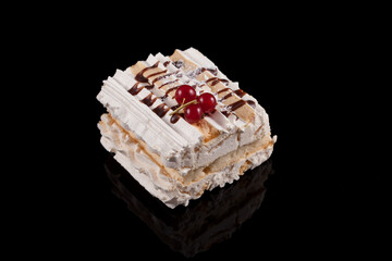 Delicious meringue cream dessert, garnished with currants and caramel syrup. Dark background with reflection, copy space