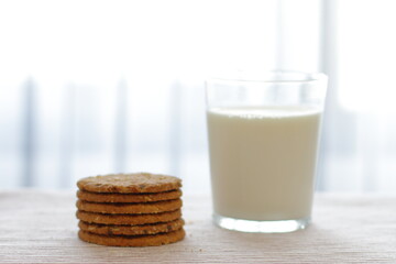 Oat cookies with glass of milk for breakfast on table cloth and blue flower on background, rustic healthy food 