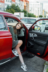 young girl at wheel of car with red interior.passenger, teenager model