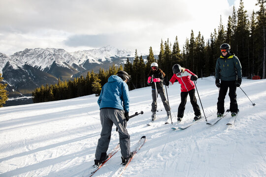 Instructor teaching skiers on snowy mountain ski slope
