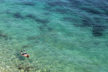 Ragazzo solitario immerso in un mare spettacolare e trasparente