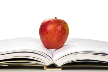 Apple. An apple upon an open book on white background.