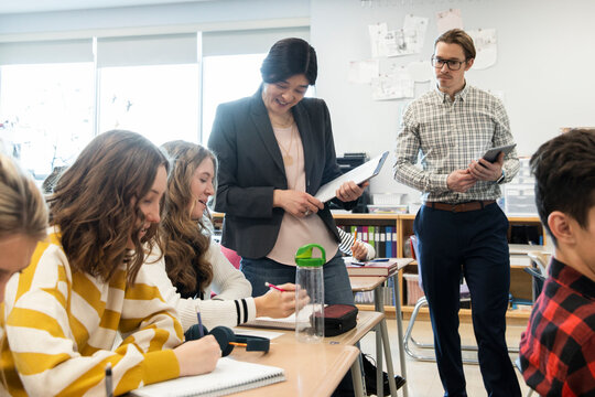 High school teachers helping students in classroom