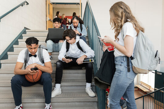 High school students hanging out with smart phones on staircase