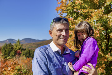 Happy man embracing his daughter on a beautoful foliage excursion