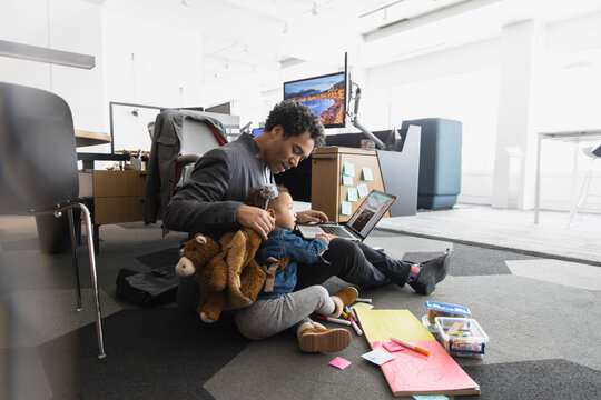 Little girl sitting on floor with father at work