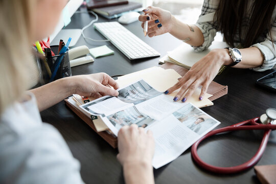 Female Doctor And Patient Reading Brochure In Office