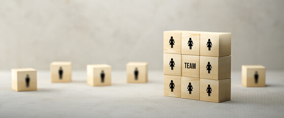 cubes with people symbols and the word TEAM on paper surface in front of concrete background