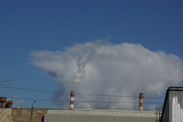 A smoking industrial chimney against a blue cloudy sky.