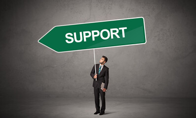 Obraz premium Young business person in casual holding road sign with SUPPORT inscription, new business direction concept