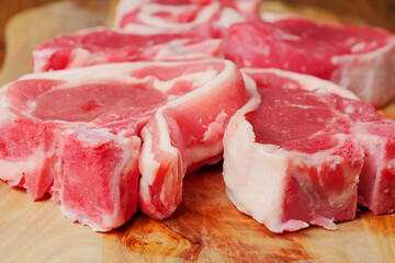 Fresh uncooked lamb loin chops on a wooden board, black background, Close up, Butcher craft concept. Selective focus.