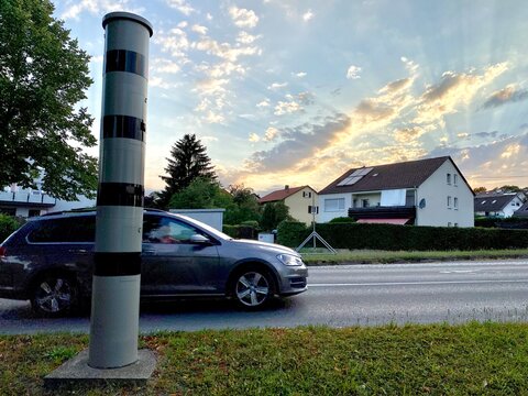 Blitzer steht am Stra&szlig;enrand ein Auto f&auml;hrt vorbei bei Abendd&auml;mmerung