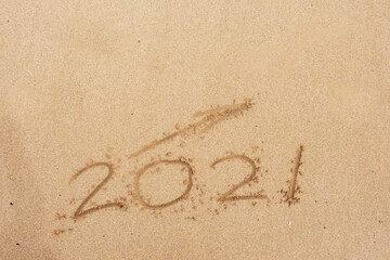 Hand written sign on a yellow warm sand 2021 and arrow going up. Positive rise in 2021 year.