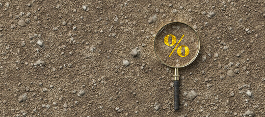 magnifying glass with percent sign on dirt gravel background