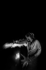 A man in white flax costume and colored smoke. Dark background