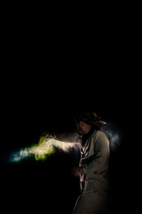 A man in white flax costume and colored smoke. Dark background