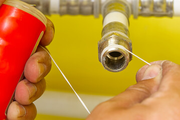 Worker installing sealing tape for water pipe fitting.Plumber putting seal tape on a thread of a...