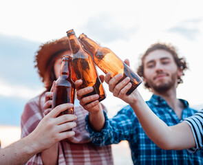 A group of happy friends are spending time relaxing on the beach and drinking beer