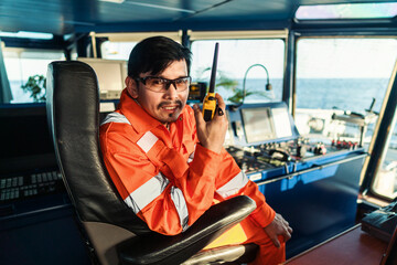 Filipino deck Officer on bridge of vessel or ship wearing coverall during navigaton watch at sea ....