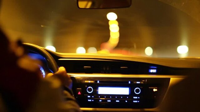 interior view from vehicle rear seat. the car is moving in the tunnel. The camera focuses on the vehicle front panel and the road. tunnel lighting and road lights can be seen.	
