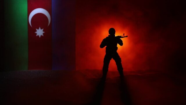 Azeri army concept. Silhouette of armed soldiers against Azerbaijani flag. Creative artwork decoration. Military silhouettes fighting scene dark toned foggy background. Selective focus