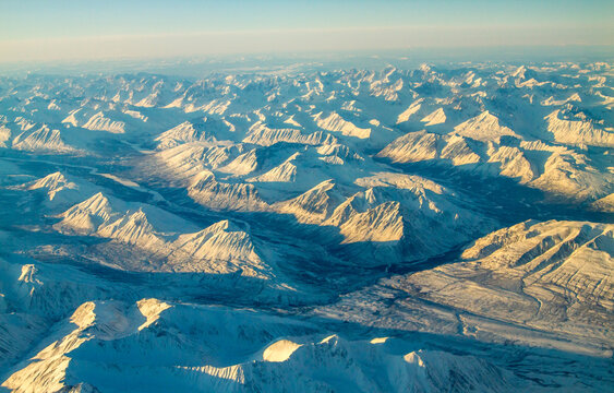 An aerial view of snow covered mountain ranges on a cold winter morning between Red Devil and Nome Alaska