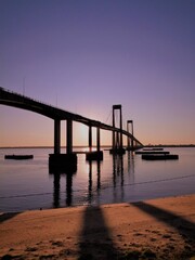 Playa, costa del río y puente al atardecer