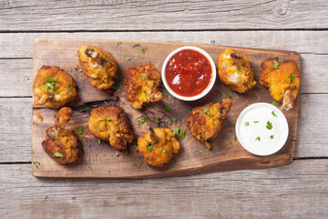 Chicken wings nuggets with sauces on wooden background .