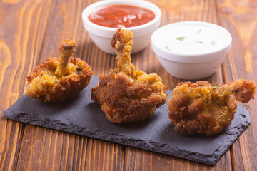 Chicken wings nuggets with sauces on wooden background .