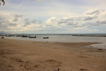 Peaceful beach with fishing boats moored in the harbor