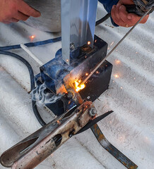 person welding iron on roof