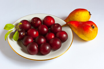 Two pears and a cherry plum in a plate.