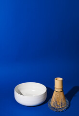 Tea whisk matches with white ceramic bowl. Ingredients for Making a Traditional Japanese Drink. Health and Alternative Medicine. Hard light in the frame. Copy space. Above. High quality photo.